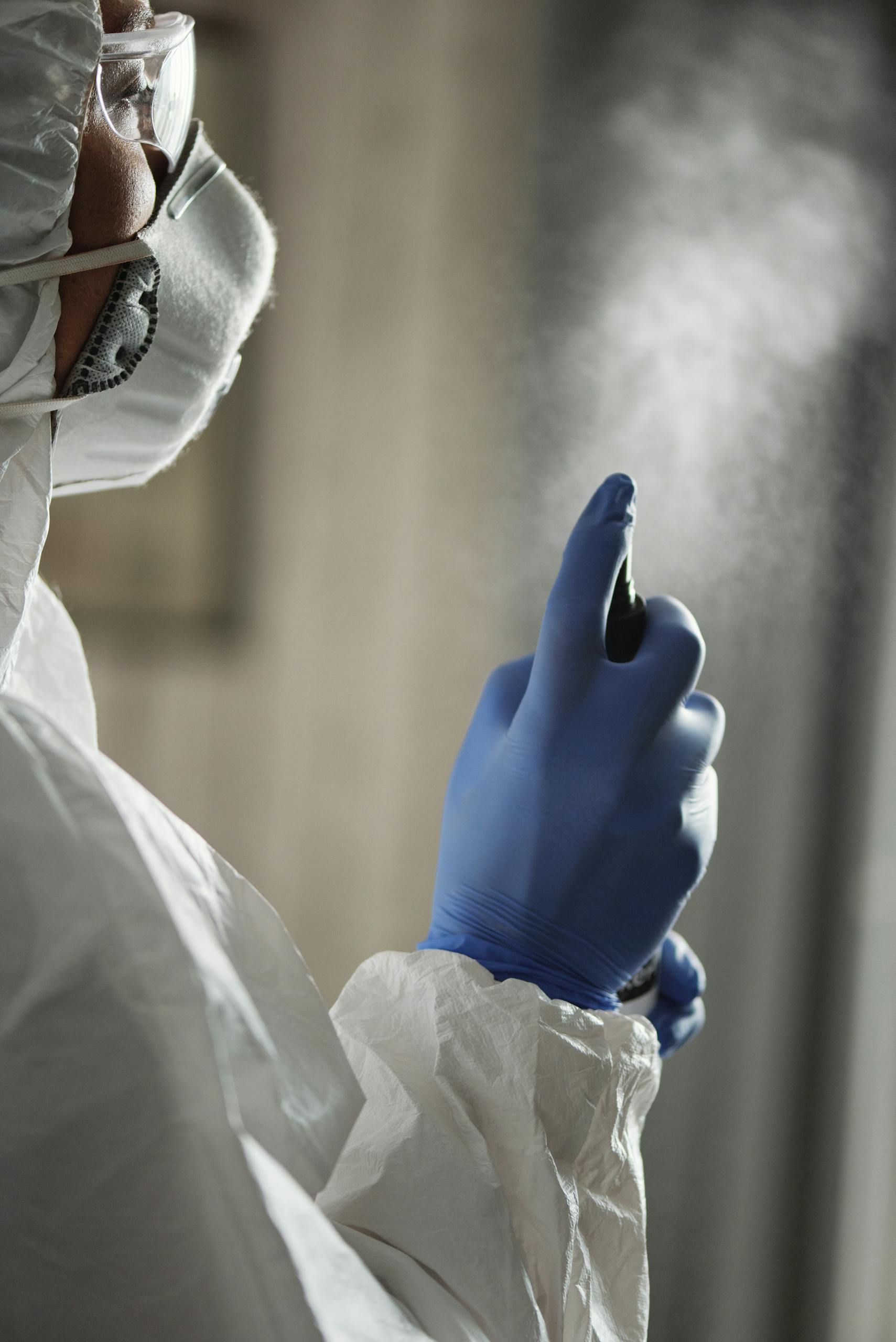 A Person in White Coverall Holding a Spray Bottle