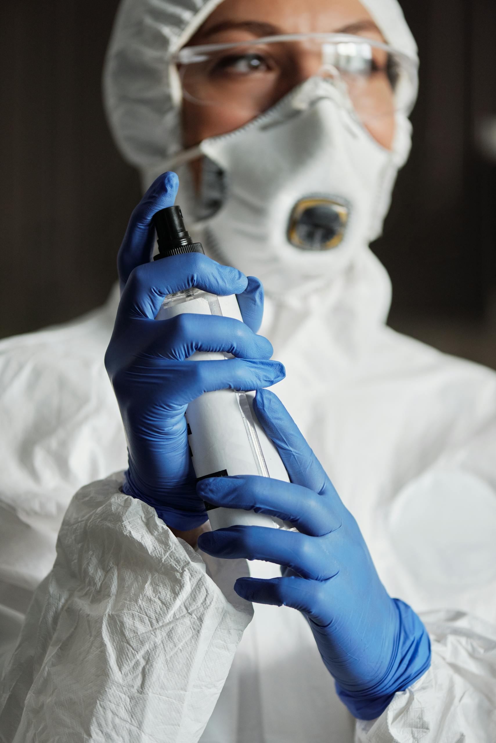 A Woman in White Coverall Holding a Spray Bottle