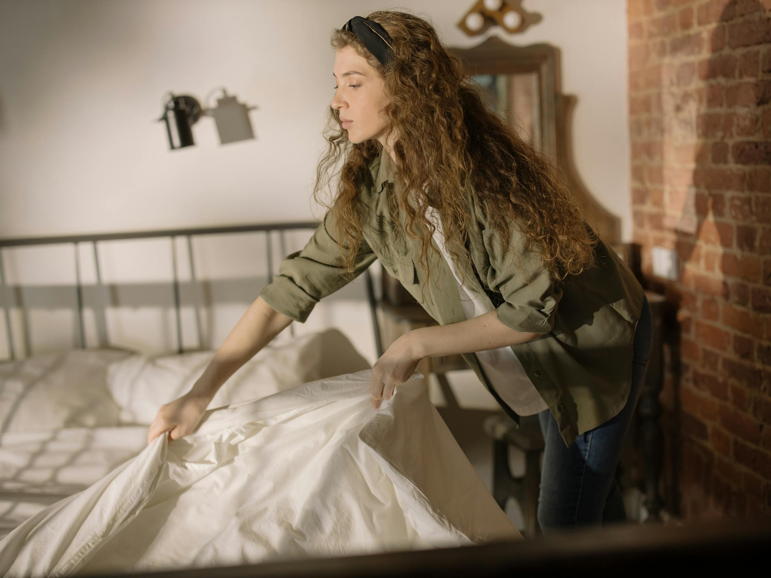 Woman in Green and Brown Camouflage Jacket and Blue Denim Jeans Holding White Textile