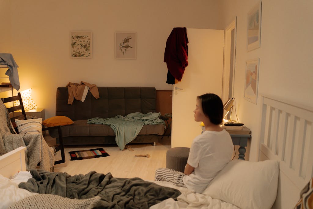 Woman in White Shirt Sitting on Bed